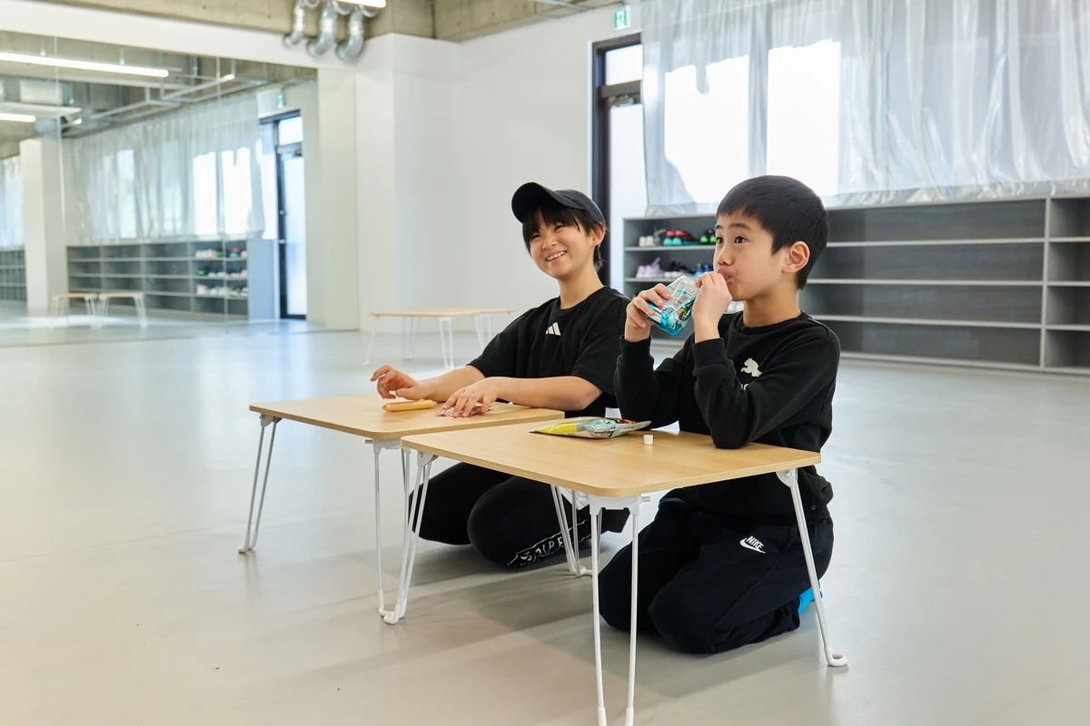 机を並べて笑顔でおやつを楽しむ子どもたち