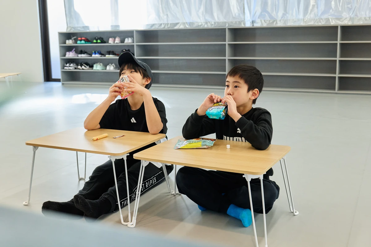 並んで座っておやつを食べる子どもたち